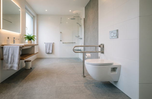 Salle de bains PMR avec WC suspendu, barres d’appui et douche accessible de plain-pied
