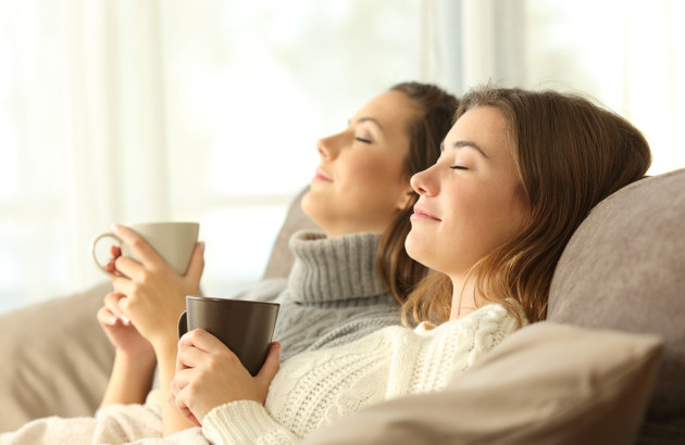 Deux femmes se détendent sur un canapé avec une boisson chaude