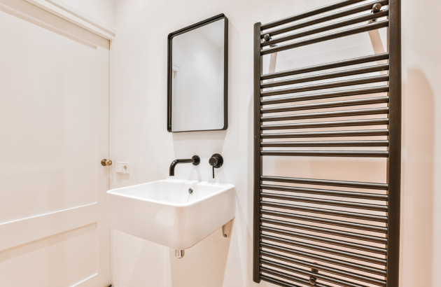 Radiateur sèche-serviettes noir dans une petite salle de bains moderne avec lavabo suspendu.