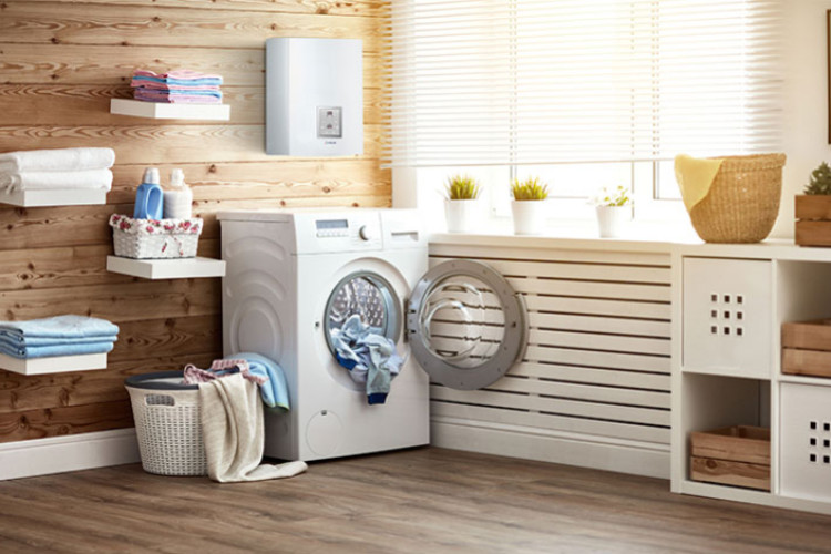 Chaudière électrique murale installée au-dessus d’un lave-linge dans une buanderie moderne avec radiateurs et rangements en bois, illustration d’un système de chauffage central compact et sans fumées.