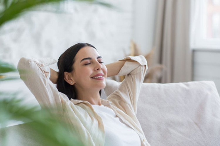 Femme détendue sur un canapé, illustrant le confort apporté par un climatiseur.
