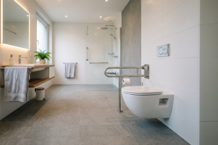 Salle de bains PMR avec WC suspendu, barres d’appui et douche accessible de plain-pied
