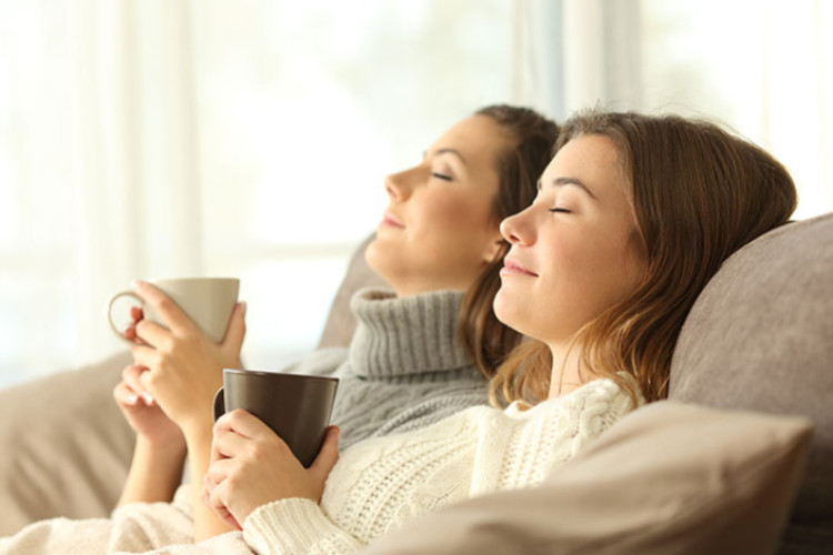 Deux femmes se détendent sur un canapé avec une boisson chaude
