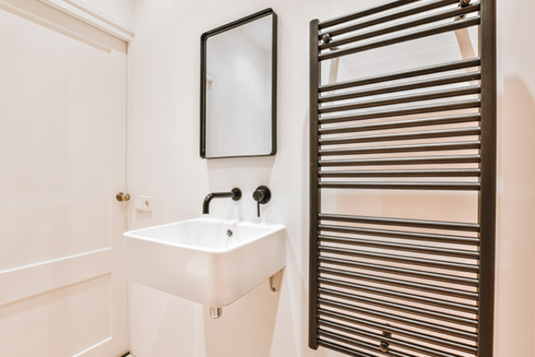 Radiateur sèche-serviettes noir dans une petite salle de bains moderne avec lavabo suspendu.