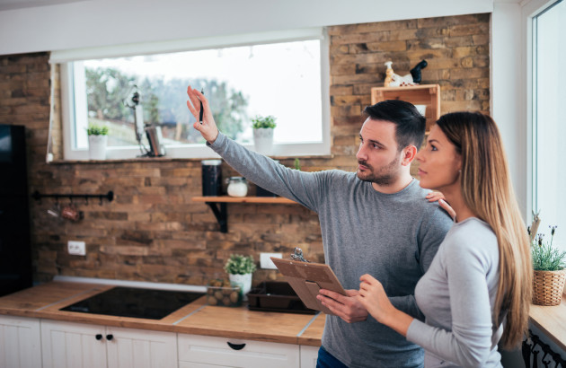 Couple discutant avec un professionnel dans une cuisine lors d’un projet de rénovation énergétique