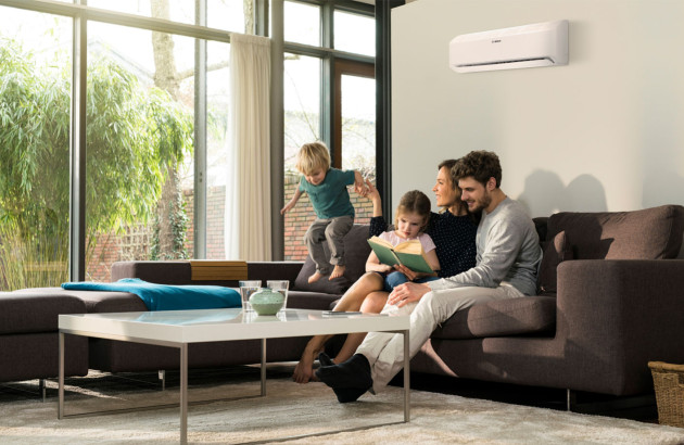 Famille qui profite d'un air frais produit par la climatisation dans le salon